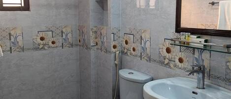 A bathroom with a toilet, bidet, and sink, all with marble-like tiles.