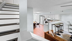 A modern kitchen with white cabinets, a central island with bar stools, and a dining area with a table and chairs. - 3BR Condo Near Ark Encounter, 8 Guests, Parking (Williamstown)