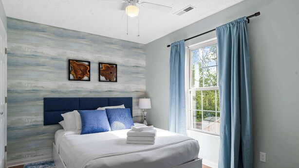 A bedroom with a large bed, a headboard, a window with curtains, and artwork on the wall. - 3BR Condo Near Ark Encounter, 8 Guests, Parking (Williamstown)