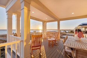 A wooden deck with chairs and a table, overlooking a body of water.