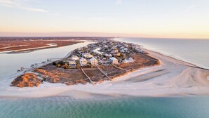 An aerial view of a coastal residential area with houses along the shoreline, a sandy beach, and a clear view of the ocean. - Freedom  Point: Oceanfront Luxury w/Pool, Game Room, Sauna & Cold Plung (Garden City Beach)