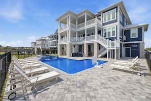 A multi-story building with a swimming pool, outdoor seating, and a fenced area. - Freedom  Point: Oceanfront Luxury w/Pool, Game Room, Sauna & Cold Plung (Garden City Beach)