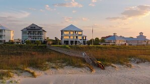 A beachfront property with a prominent house, a wooden staircase leading to the beach, and a flagpole. - Freedom  Point: Oceanfront Luxury w/Pool, Game Room, Sauna & Cold Plung (Garden City Beach)