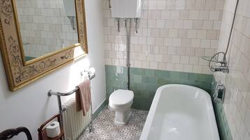 Un baño con bañera, inodoro y radiador.