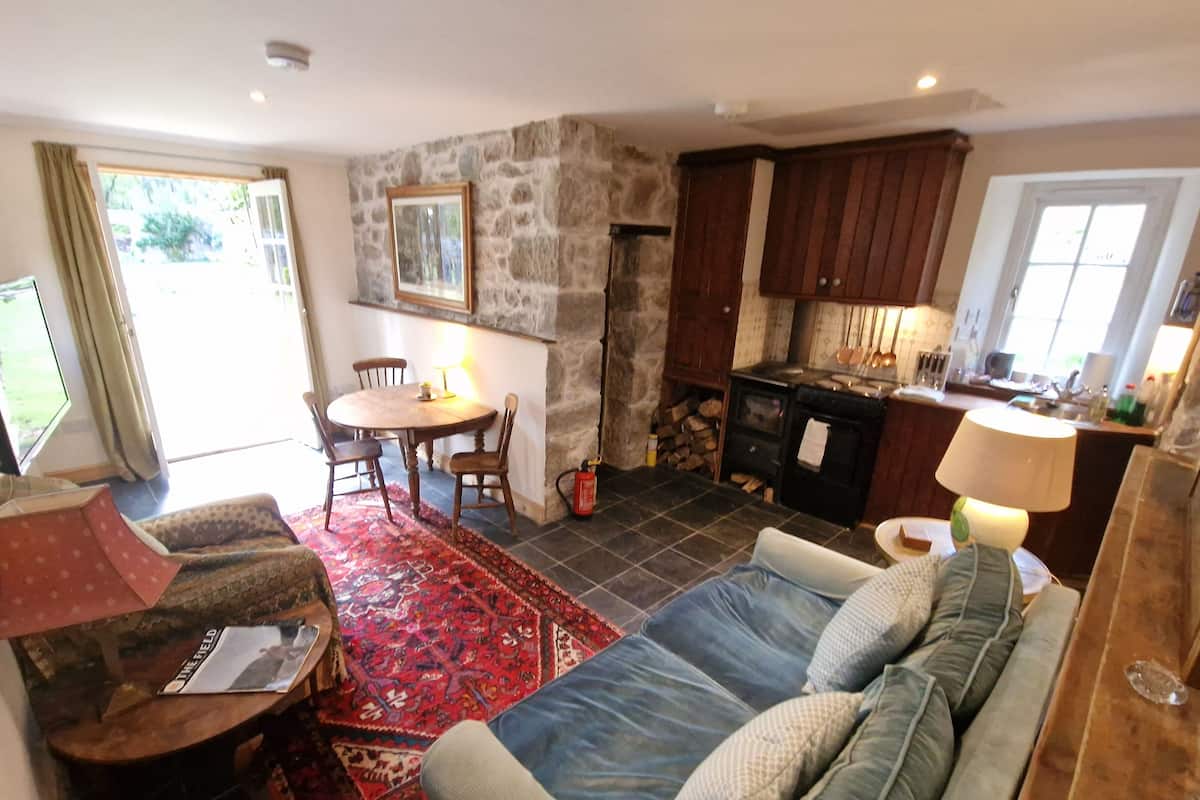 A cozy living room with a sofa, a coffee table, and a rug. There's a stone wall and wooden cabinets in the background.