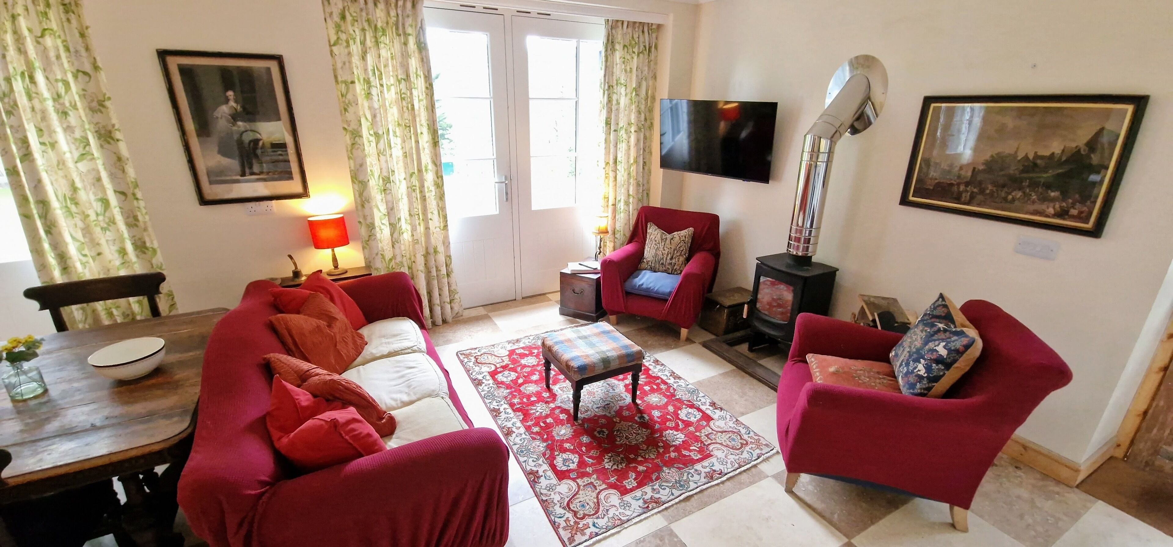 A living room with a sofa, armchair, and ottoman, a television, a fireplace, and a dining area with a table and chairs.