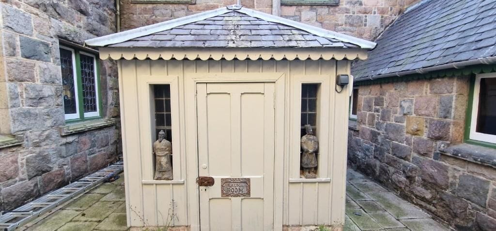 A small, single-room structure with a door and two windows, labeled as a 'Sitting Room.'