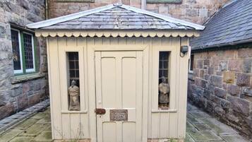 A small, single-room structure with a door and two windows, labeled as a 'Sitting Room.'