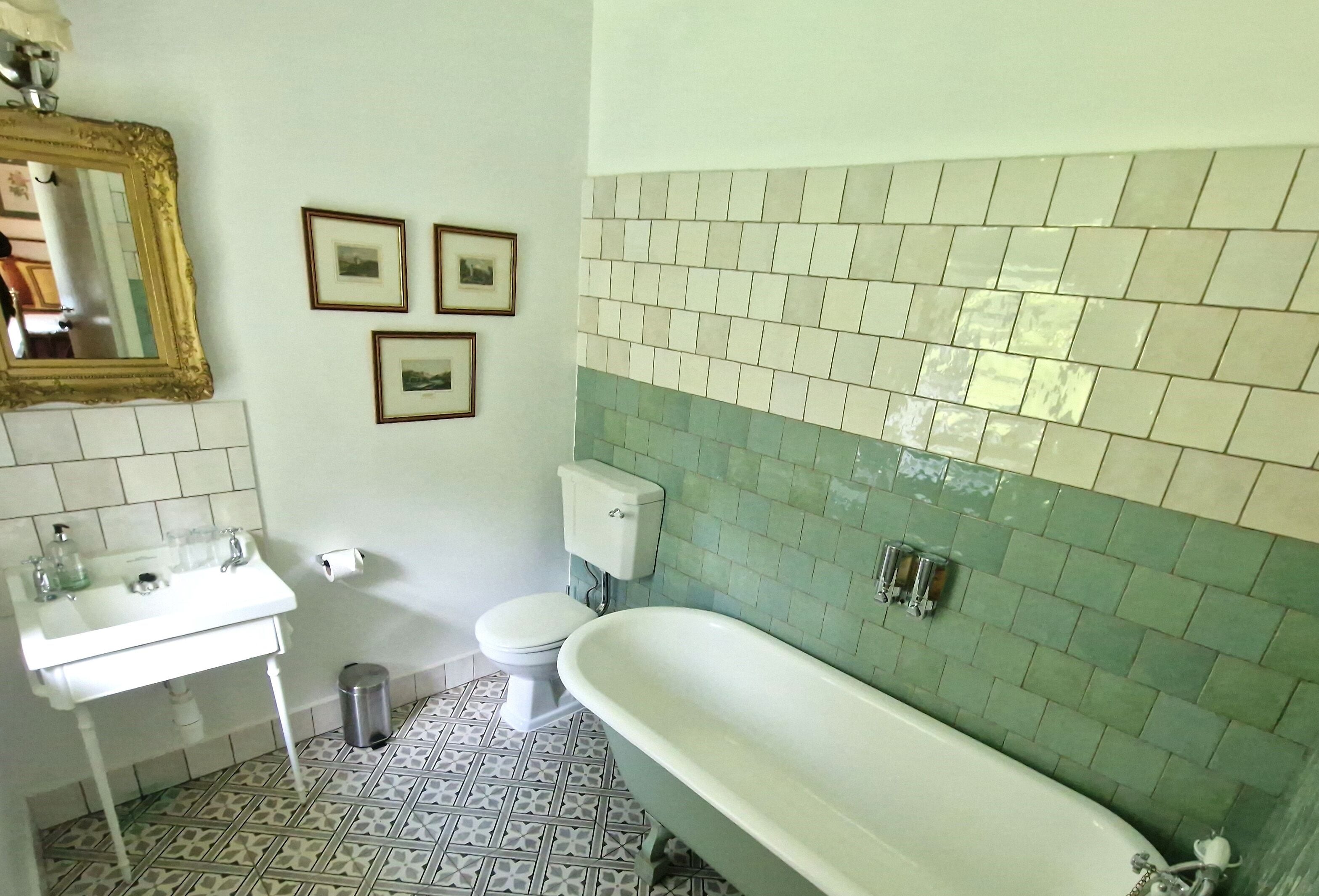 A bathroom with a white sink, toilet, and bathtub. There are three framed pictures on the wall.