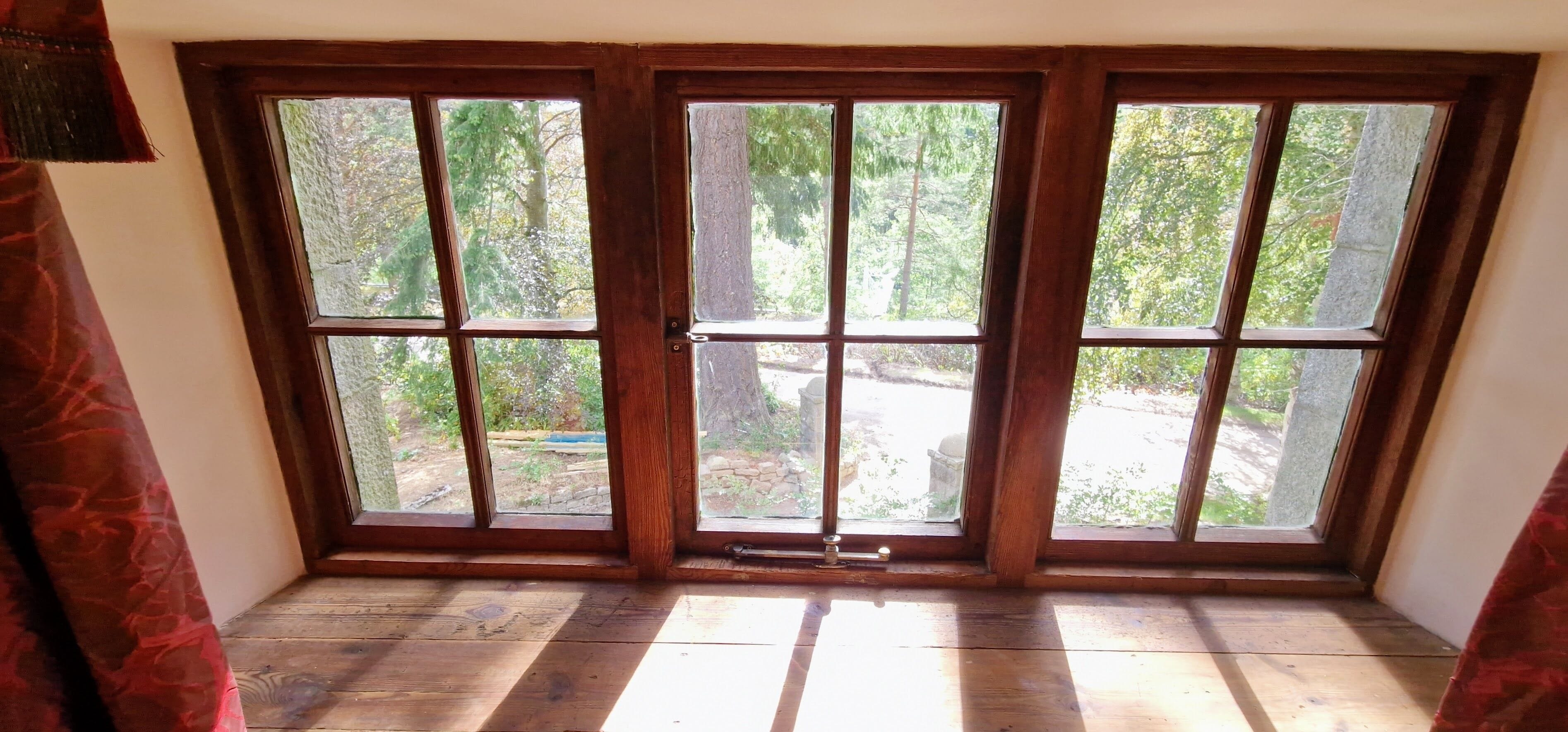 Una habitación con un ventanal grande de madera que da a un jardín.