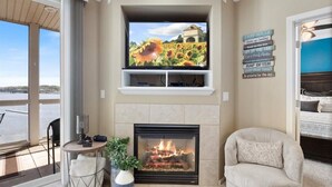 A living room with a fireplace, a television mounted above it, and a view of the outdoors. - Immaculate Lands End #735 3Bed/2Bath New Remodel! (Osage Beach)