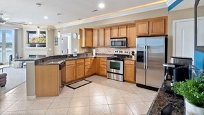A modern kitchen with granite countertops, stainless steel appliances, wooden cabinets, and a large island. - Immaculate Lands End #735 3Bed/2Bath New Remodel! (Osage Beach)