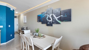 A dining area with a white table, four chairs, and a wall-mounted art piece. - Immaculate Lands End #735 3Bed/2Bath New Remodel! (Osage Beach)