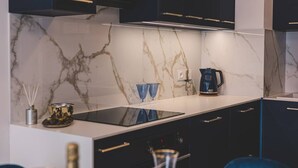 A modern kitchen with dark cabinets, a marble backsplash, and a black induction cooktop. - Linterna Luksus nad Ba Tykiem Let s Sea G ski SPA (Mielno)