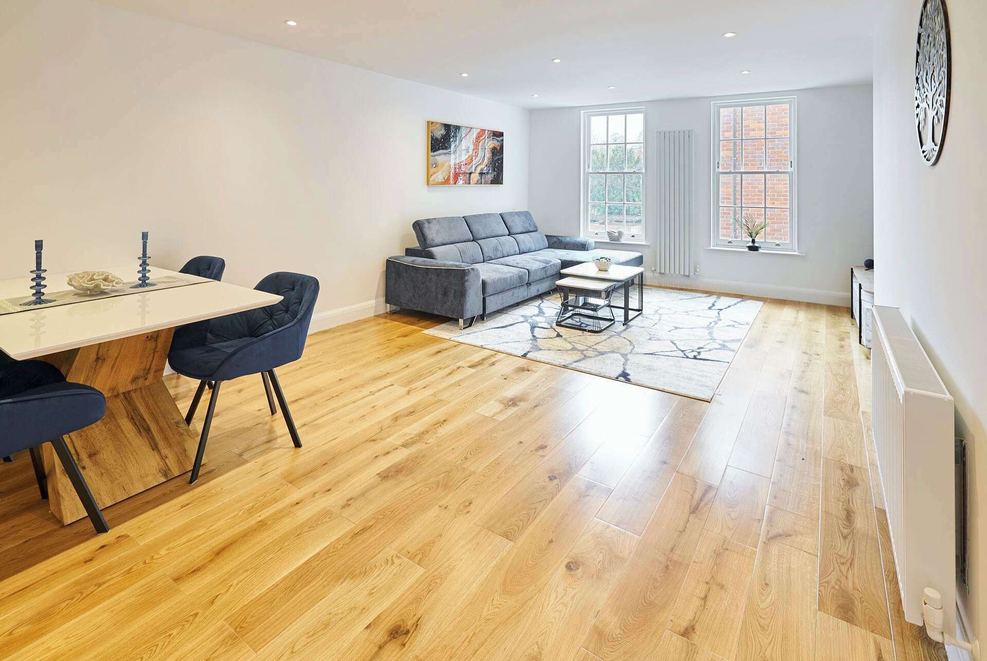 A modern living room with a grey sofa, a dining table with chairs, and a coffee table.