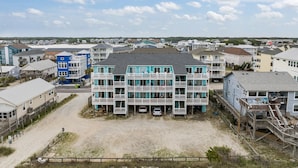 A beachfront building with multiple balconies, a sandy area in front, and a view of the beach and other buildings in the background. - Top Floor 2 Bdrm/2 Bath OCEAN FRONT,BEACH ACCESS condo.  Sleeps 6 with Linens! (Carolina Beach)