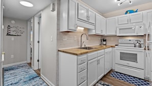 A modern kitchen with white cabinetry, a wooden countertop, a built-in microwave, and an oven. - Top Floor 2 Bdrm/2 Bath OCEAN FRONT,BEACH ACCESS condo.  Sleeps 6 with Linens! (Carolina Beach)