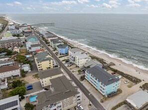 Una zona residencial costera con playa, un muelle y una hilera de edificios coloridos a lo largo de la orilla.