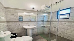 Een moderne badkamer met een douchecabine van glas, een wit wastafelmeubel en een toilet.