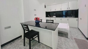 Een moderne keuken met witte kasten, een zwart aanrecht en een bloemenvaas op het eiland.