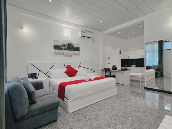 Un dormitorio moderno con una cama grande, un sofá gris, un escritorio y un televisor.