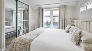 Un dormitorio amplio con una cama grande, una puerta corrediza de vidrio que da a un balcón y vistas al exterior.