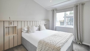 A bedroom with a bed, a bedside table, a window with curtains, and a view of the outside. - Host & Stay | Transporter Lodge (Great Ayton)