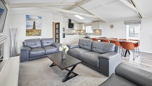 A modern living room with a sectional sofa, a coffee table, and a dining area with orange chairs.