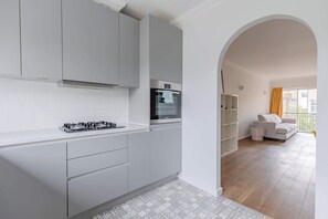 A modern kitchen with grey cabinets, a built-in oven, and a gas stove.