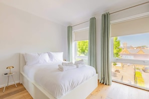 Ein Schlafzimmer mit einem großen Bett, einem Nachttisch und einem Fenster mit Vorhängen.