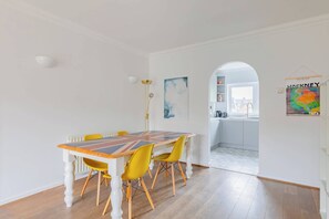 A dining area with a table and chairs, a radiator, and a view into another room.