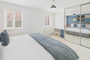 A bedroom with a bed, a desk, a chair, and a wardrobe.