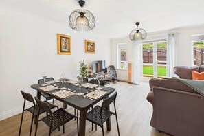 A dining area with a table set for four, a sofa, and a TV in the background.