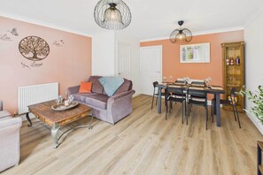 A cozy living room with a sofa, a coffee table, and a dining area with a table and chairs.
