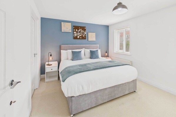 A bedroom with a bed, bedside tables, a lamp, and artwork on the wall.
