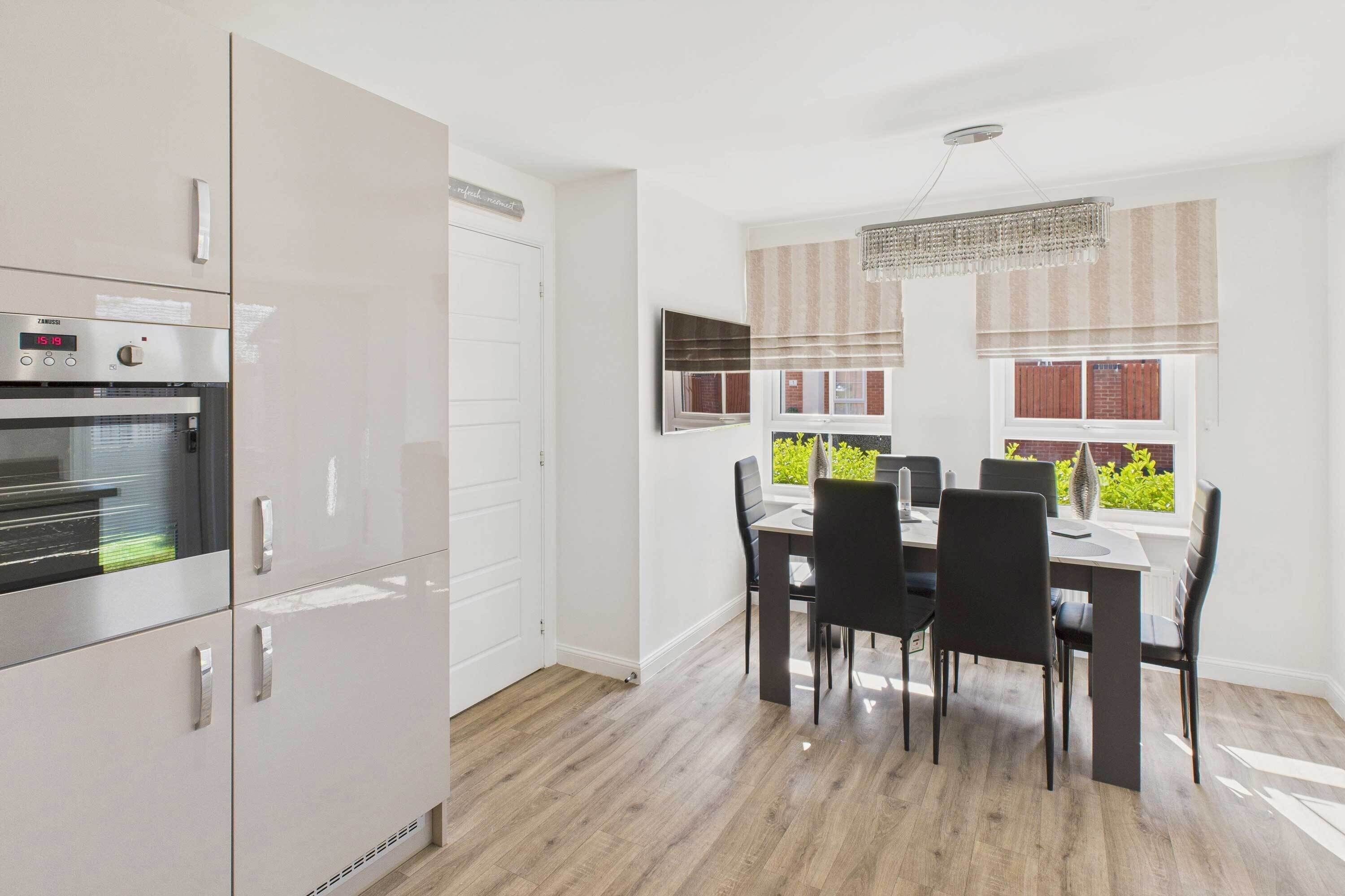 A modern kitchen with a built-in oven and a dining area with a table and chairs.
