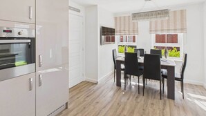 A modern kitchen with a built-in oven and a dining area with a table and chairs. - Host & Stay | Orient House (Yarm)