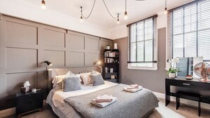 A modern bedroom with a large bed, bedside tables, a desk, and a bookshelf. - Fabulous Solihull Luxury Designer Apartment 3BR (West Midlands)