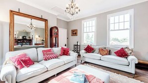 A living room with two white sofas, a chandelier, a large mirror, and a fireplace. - Fabulous Solihull Luxury Designer Apartment 3BR (West Midlands)