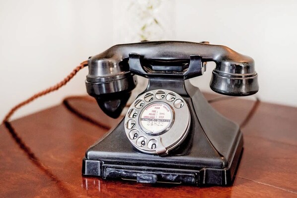 Un teléfono antiguo de disco giratorio sobre una superficie de madera.