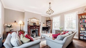 A living room with two grey sofas, a fireplace, a chandelier, and a bookshelf. - Fabulous Solihull Luxury Designer Apartment 3BR (West Midlands)