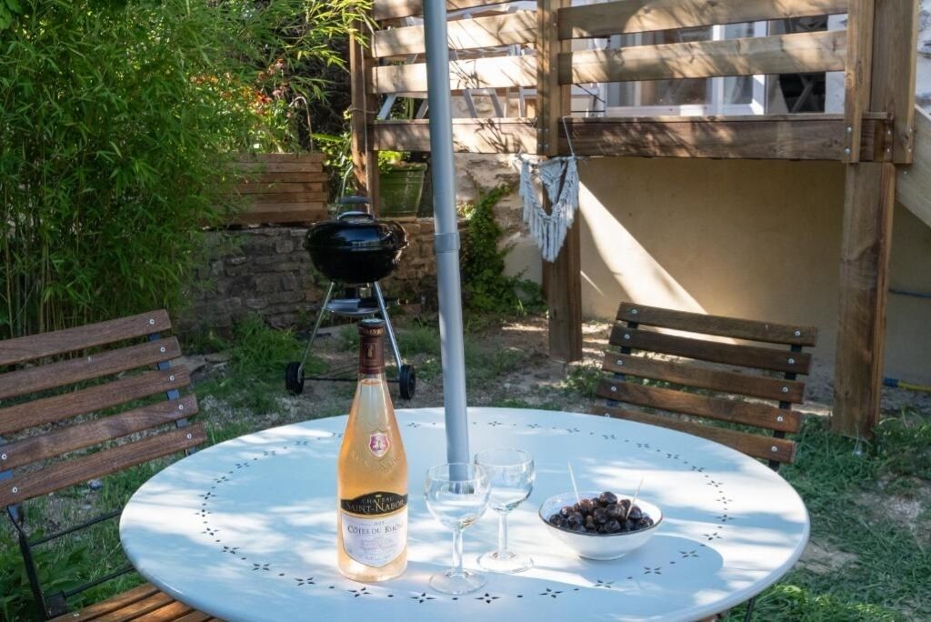 Una mesa redonda con una botella de vino, dos copas de vino y un bol de aceitunas.