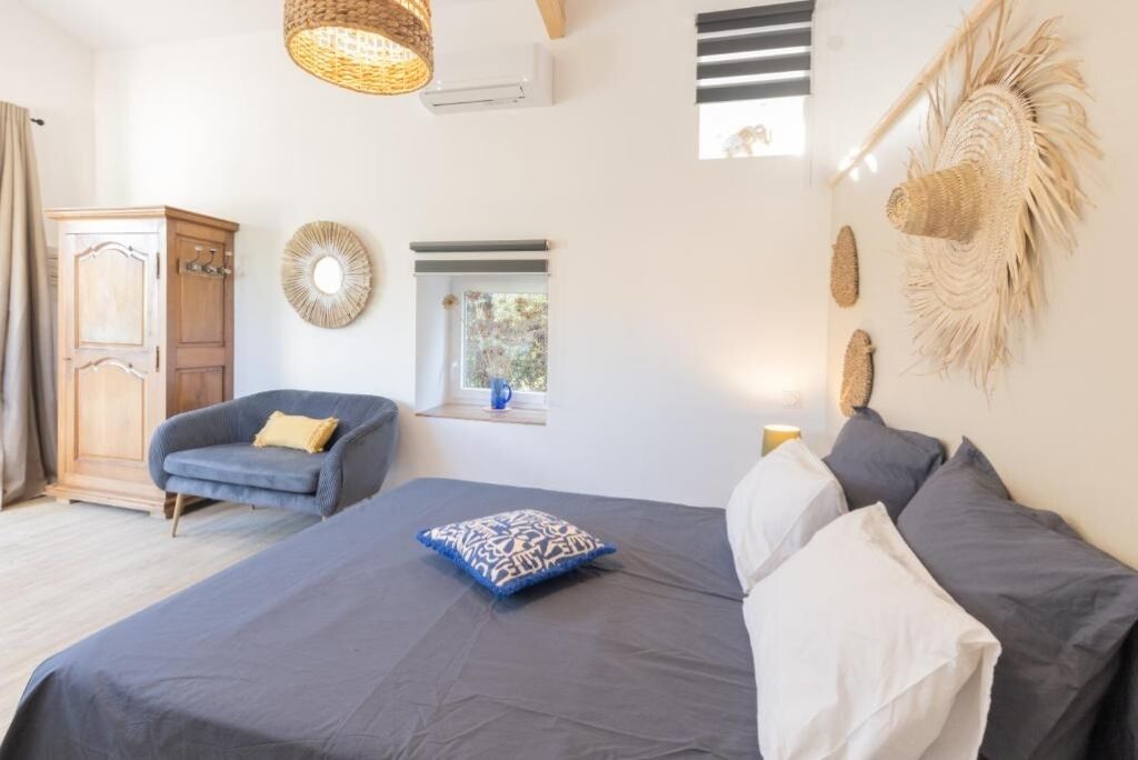 A bedroom with a bed, a chair, a wardrobe, and a window.