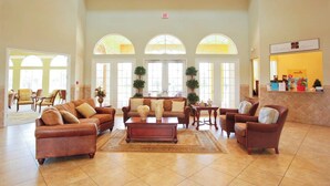 A spacious lobby with a brown leather sofa, a wooden coffee table, and a reception desk. - Ground Floor Gathering up to 9 Guests BL387 (Kissimmee)