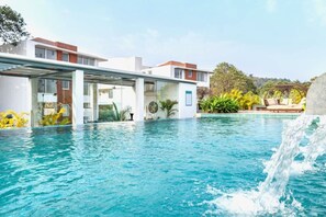 Un hôtel moderne doté d’une piscine, d’un espace extérieur couvert et d’une cascade décorative.