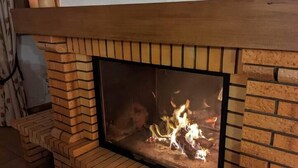 Een bakstenen schoorsteen met glazen deurtje, een houten bovenkant en een brandend vuur.