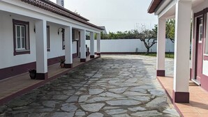 Ein Gebäude mit einem gepflasterten Innenhof, weißen Wänden mit roter Umrandung und einem Wellblechzaun im Hintergrund.