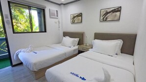 Une chambre d’hôtel avec deux lits, une fenêtre et des œuvres d’art accrochées aux murs.