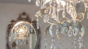 A chandelier with crystal decorations and a mirror below it. - Tide & Teacups (Brighton)