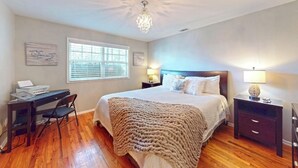 A bedroom with a large bed, a desk with a laptop, and a chandelier.